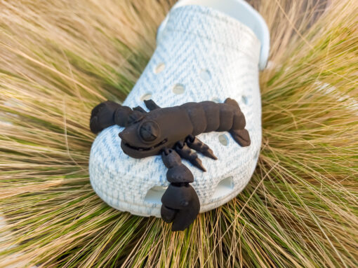 Colorful 3D printed flexi lobster charms in green, orange, yellow, and red, attached to Crocs shoes. Each lobster has a segmented, flexible body and realistic details, adding a playful marine-inspired style to the shoes.