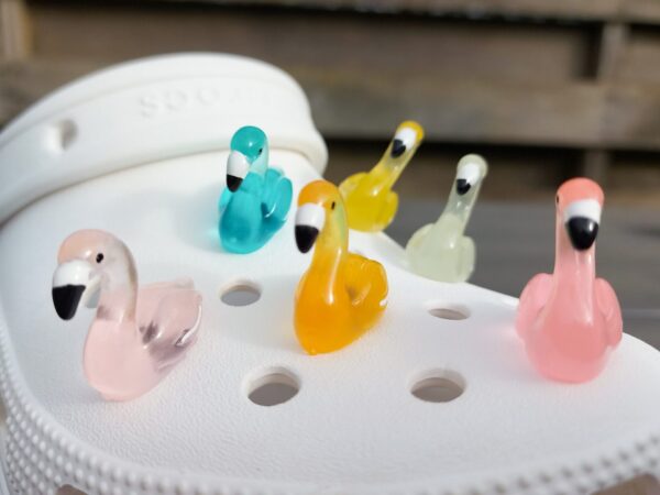 Glow in the dark flamingo shoe charms on a pair of Crocs shoes. Different colors such as pink, orange, blue, purple and green.