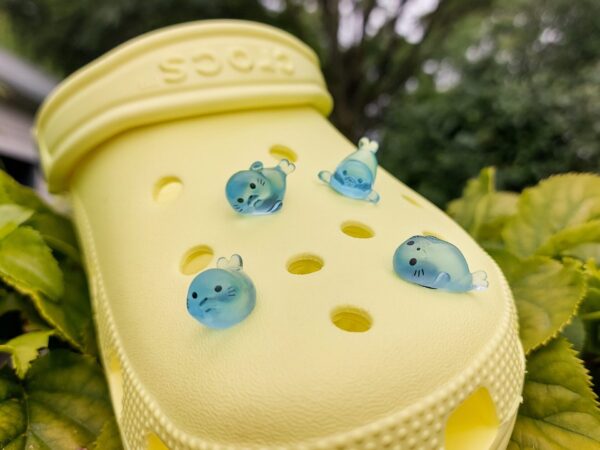 Glow in the dark seal shoe charms on a pair of Crocs shoes. The seals are made of resin and are each in different playful positions.