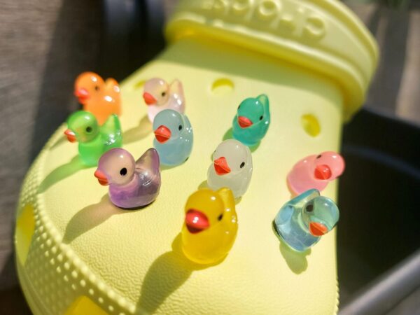 Glow in the dark duck shoe charms on a pair of Crocs shoes. The ducks resemble a rubber bath duckie.