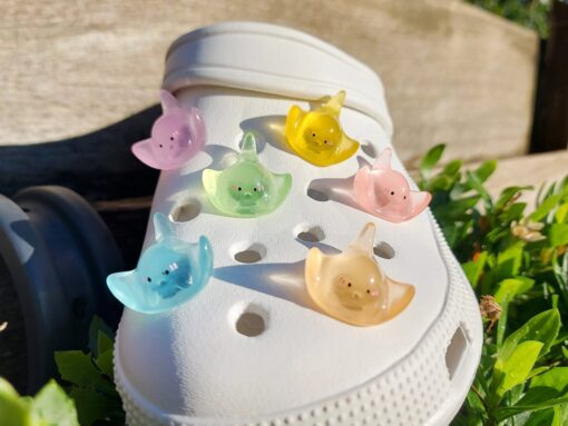Glow-in-the-dark manta ray charms on a Croc shoe. These enchanting accessories light up in the dark, adding a marine-inspired touch to your footwear. Perfect for customizing your Crocs with a unique and magical ocean theme.
