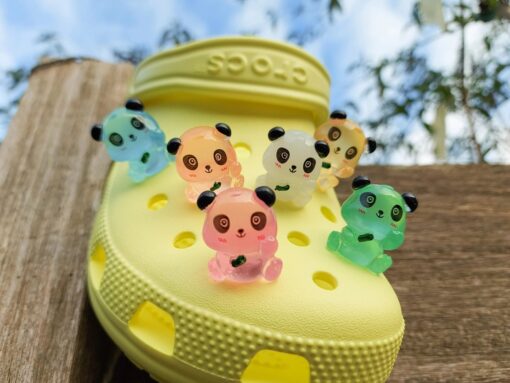 Set of glow in the dark panda croc charms displayed on a Croc shoe. The charms feature small panda bears in various colors, with a glowing effect. These adorable accessories are designed to light up in the dark.