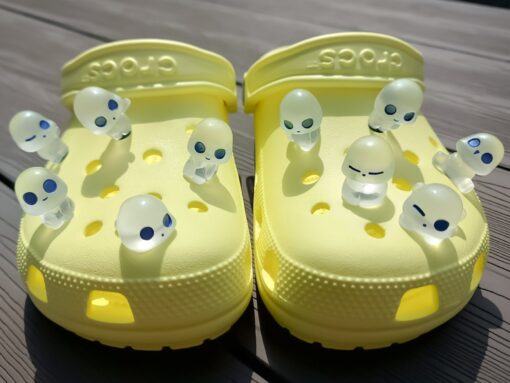 Yellow Crocs adorned with 10 glowing charms resembling ghosts, aliens, or elves. These fun and whimsical glow-in-the-dark charms add a unique touch to your Crocs, perfect for making your footwear stand out in the dark.