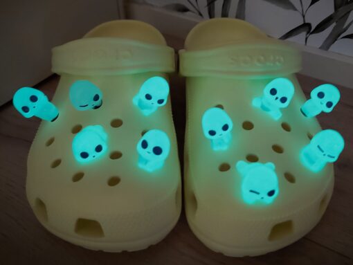 Yellow Crocs adorned with 10 glowing charms resembling ghosts, aliens, or elves. These fun and whimsical glow-in-the-dark charms add a unique touch to your Crocs, perfect for making your footwear stand out in the dark.