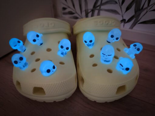 Yellow Crocs adorned with 10 glowing charms resembling ghosts, aliens, or elves. These fun and whimsical glow-in-the-dark charms add a unique touch to your Crocs, perfect for making your footwear stand out in the dark.