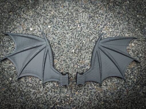 3d-printed bat or dragon wings shoe charms on a pair of Crocs shoes. They look halloween themed.