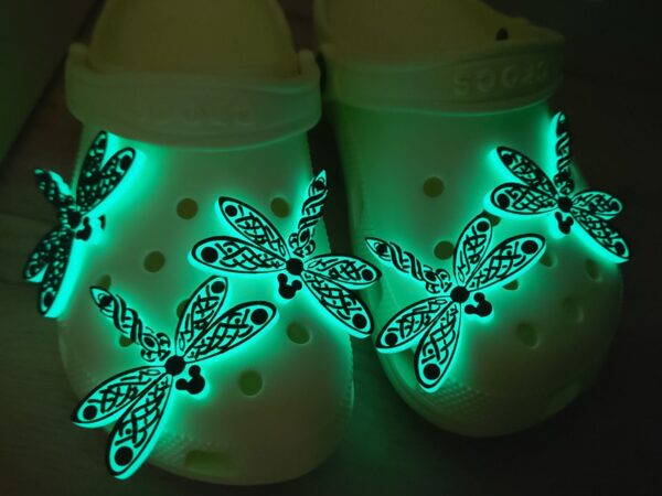 3D-printed glow-in-the-dark dragonfly charm with a Celtic weave pattern on a Croc shoe. The intricate design adds a whimsical and enchanting touch to the footwear, perfect for day or night style.