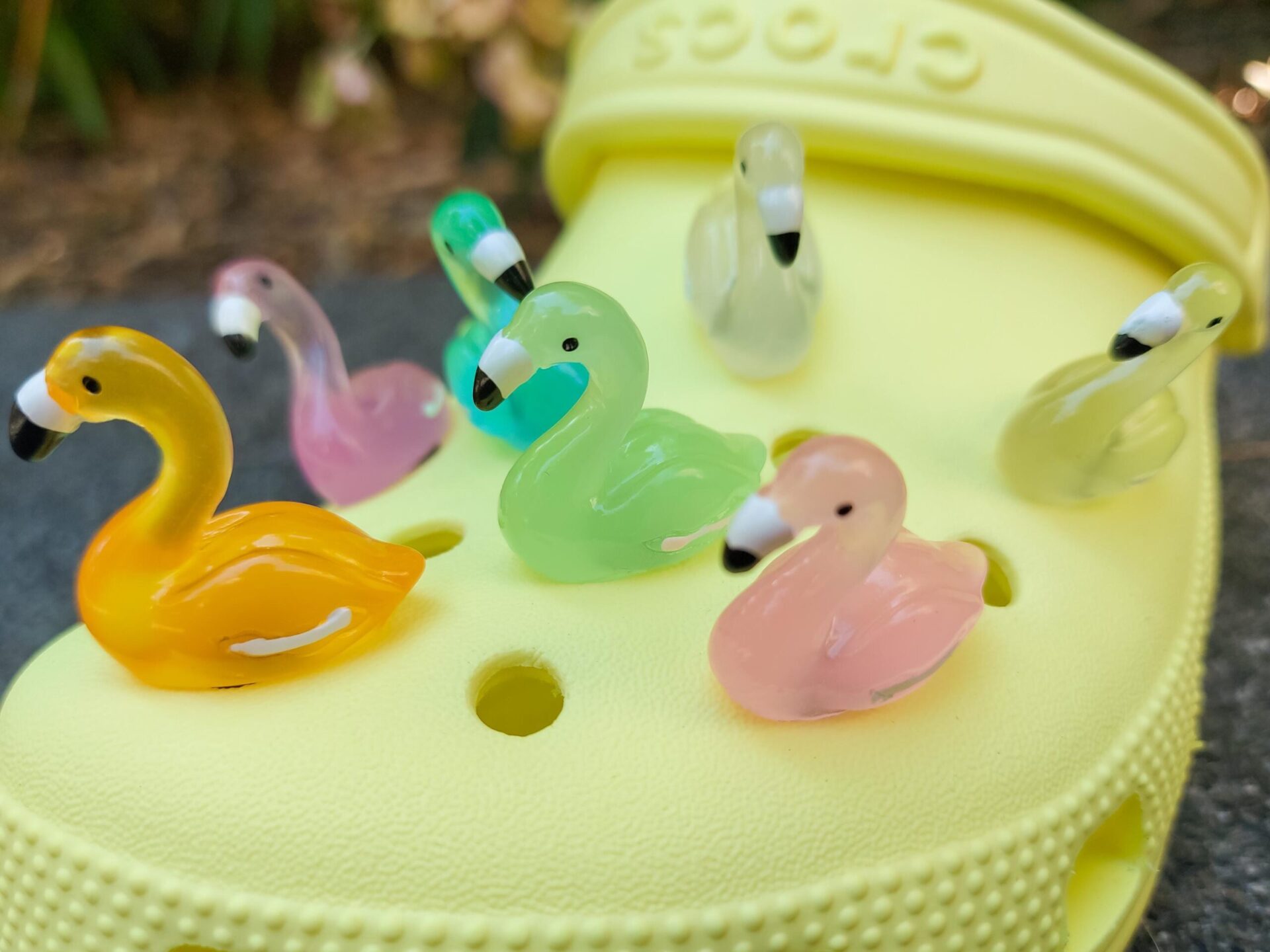Glow in the dark flamingo shoe charms on a pair of Crocs shoes. Different colors such as pink, orange, blue, purple and green.