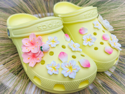 An 18-piece Sakura flower charm set featuring soft pink and white cherry blossom designs for Crocs. The delicate charms are arranged to resemble blooming sakura flowers offering a peaceful and elegant floral theme for personalized footwear decoration