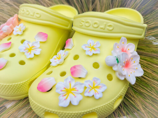 An 18-piece Sakura flower charm set featuring soft pink and white cherry blossom designs for Crocs. The delicate charms are arranged to resemble blooming sakura flowers offering a peaceful and elegant floral theme for personalized footwear decoration