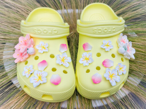 An 18-piece Sakura flower charm set featuring soft pink and white cherry blossom designs for Crocs. The delicate charms are arranged to resemble blooming sakura flowers offering a peaceful and elegant floral theme for personalized footwear decoration