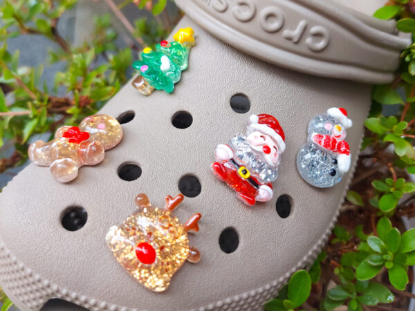 A glittery Christmas-themed set of five Croc charms featuring a gingerbread man, reindeer, snowman, Santa, and a Christmas tree. Each charm has a sparkling glitter finish, adding a festive and playful holiday touch to your Crocs.