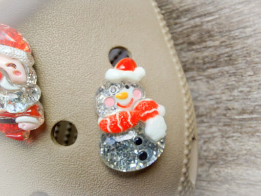 A glittery Christmas-themed set of five Croc charms featuring a gingerbread man, reindeer, snowman, Santa, and a Christmas tree. Each charm has a sparkling glitter finish, adding a festive and playful holiday touch to your Crocs.