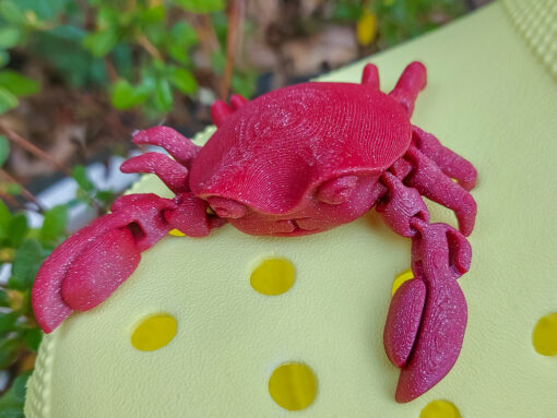 A 3D-printed, flexible red crab charm attached to a yellow Croc shoe. The crab charm features articulated claws and realistic texture, adding a fun and beach-inspired touch to the footwear. Perfect for ocean lovers and those seeking unique shoe accessories.