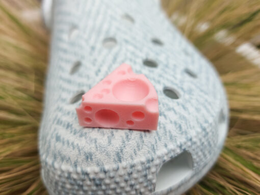 Close-up of a pair of light blue shoes decorated with colorful 3D-printed cheese wedge charms in shades of yellow, orange, and pink. The cheese charms feature realistic holes and a playful, quirky design, adding a fun pop of color to the footwear.